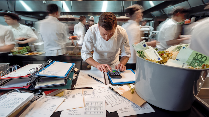 chef_calculating Koch kalkuliert in hektischer Küche